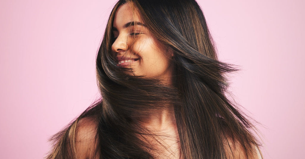 A young woman shakes her head from side to side, sending her dark brown hair in various directions.